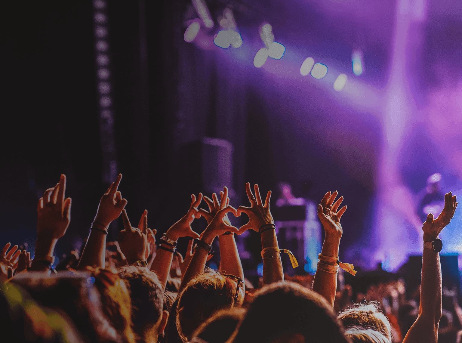 Crowd raises hands in excitement at live music performance. Overlaid is the German word "Konzert" with its English translation, "concert".