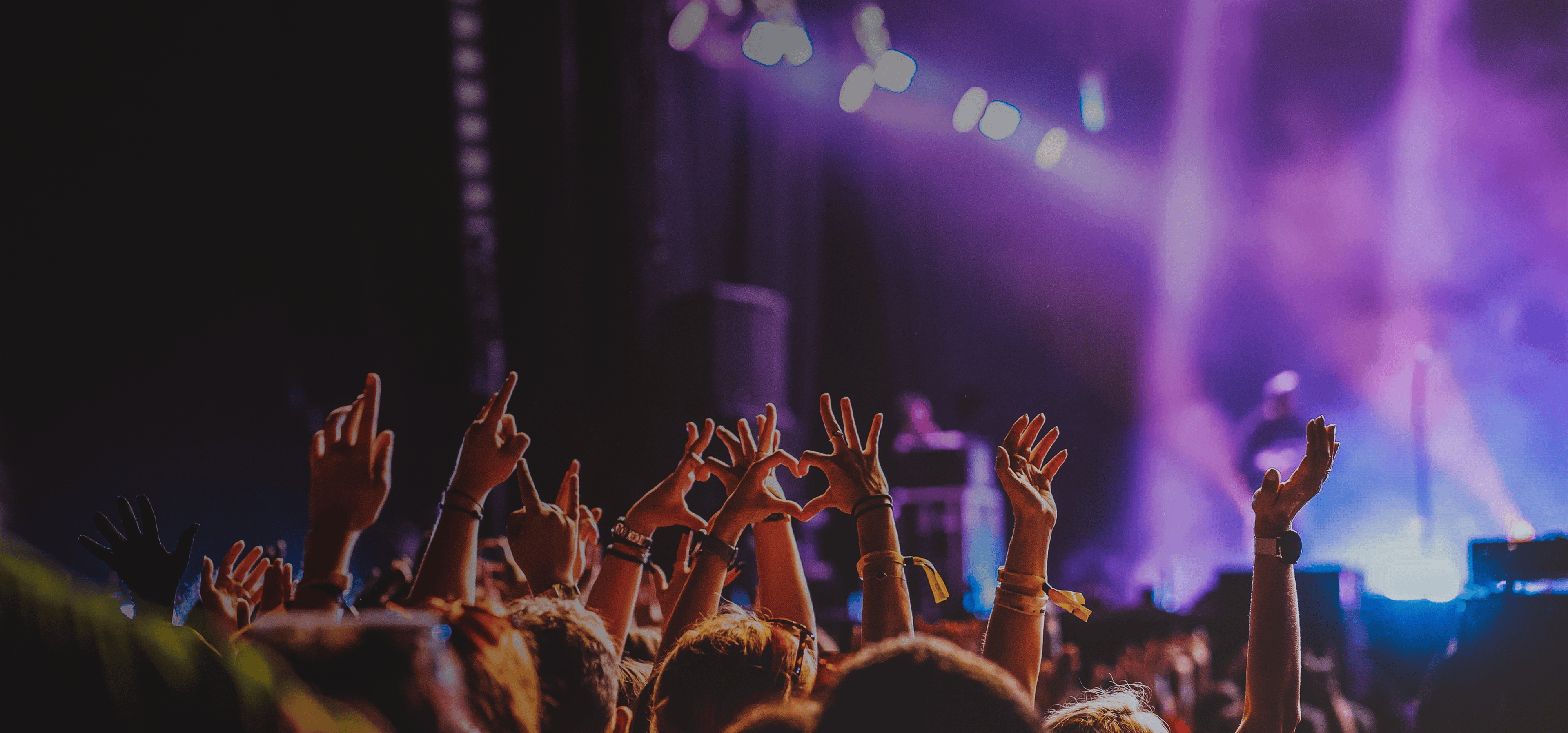 Crowd raises hands in excitement at live music performance. Overlaid is the German word "Konzert" with its English translation, "concert".