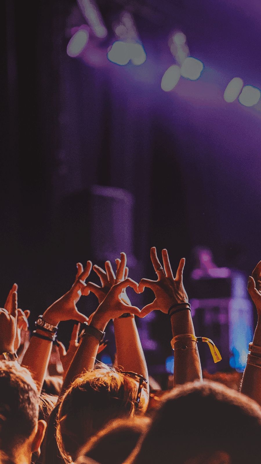 Crowd raises hands in excitement at live music performance. Overlaid is the German word "Konzert" with its English translation, "concert".