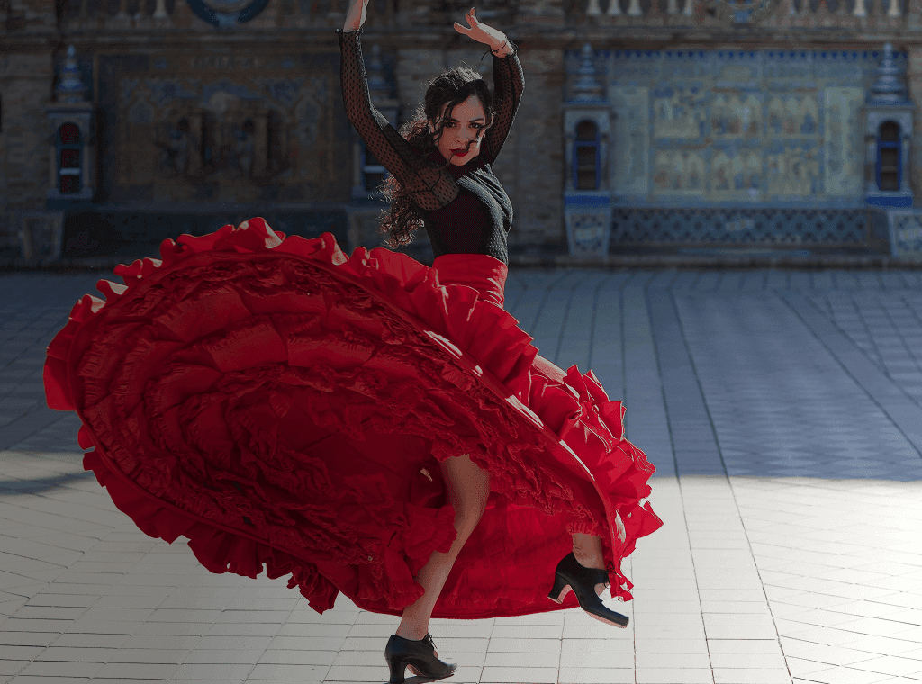 Flamenco dancer twirls in front of grand building backdrop. Overlaid is the Spanish word "bailar" with its English translation, "to dance".