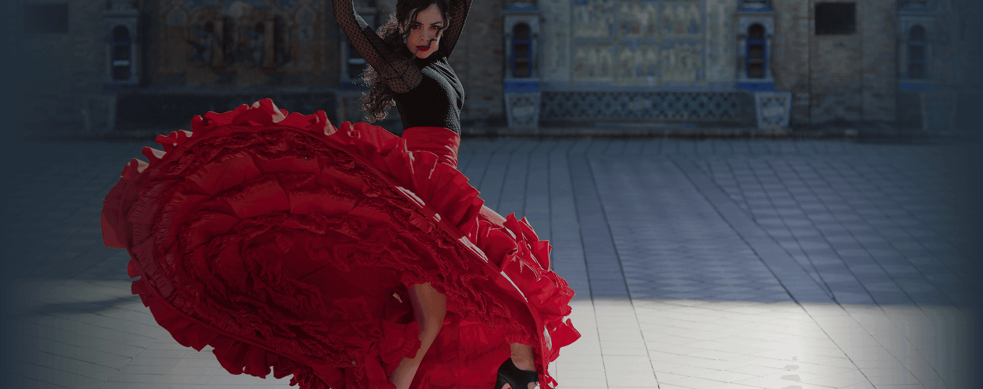 Flamenco dancer twirls in front of grand building backdrop. Overlaid is the Spanish word "bailar" with its English translation, "to dance".