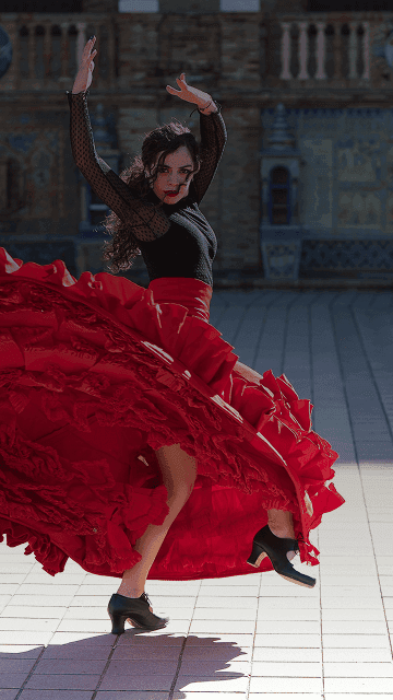 Flamenco dancer twirls in front of grand building backdrop. Overlaid is the Spanish word "bailar" with its English translation, "to dance".